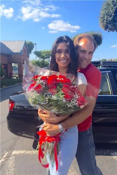 nikki en mark skoenmaker staan saam buite huis op straat nikki hou boeket rooi rose vas